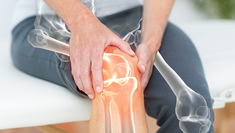 Woman holding her knee in pain from osteoarthritis