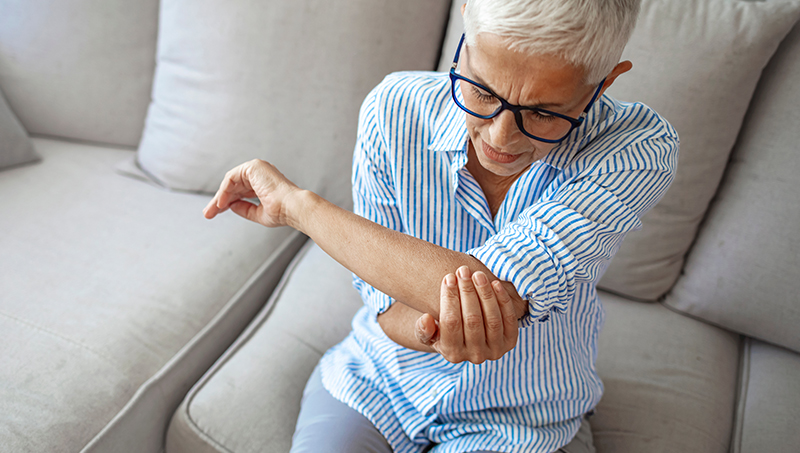 Woman holding elbow in pain due to elbow bursitis