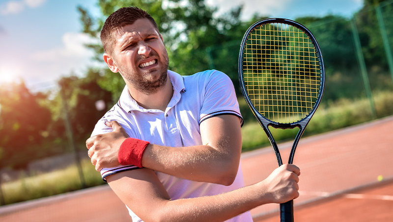 man holding shoulder in pain due to rotator cuff tear from playing tennis